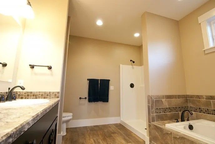A bathroom with a tub , sink , toilet and shower.