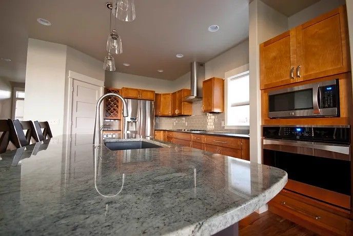 A kitchen with granite counter tops , stainless steel appliances , and wooden cabinets.