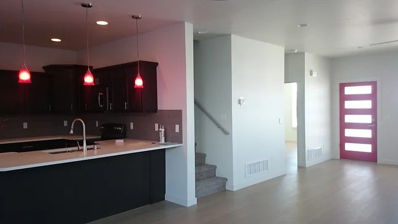 A kitchen with black cabinets and a pink door