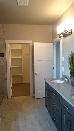 A bathroom with a sink and a walk in closet.