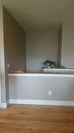 An empty room with a wooden floor and a gray wall.