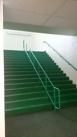A set of green stairs with a green railing