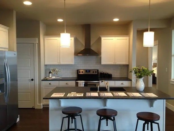 A kitchen with white cabinets and black counter tops