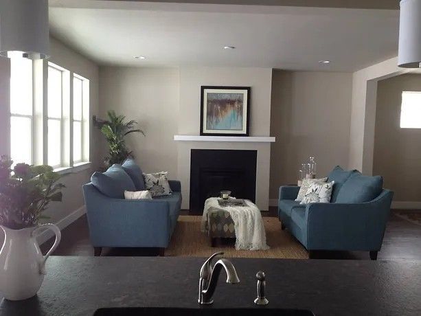 A living room with two blue couches and a fireplace