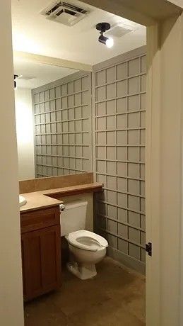 A bathroom with a toilet , sink and mirror.