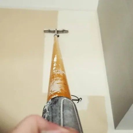 A person is using a vacuum cleaner to clean a wall.