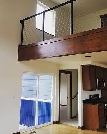 A living room with a balcony and sliding glass doors leading to a kitchen.
