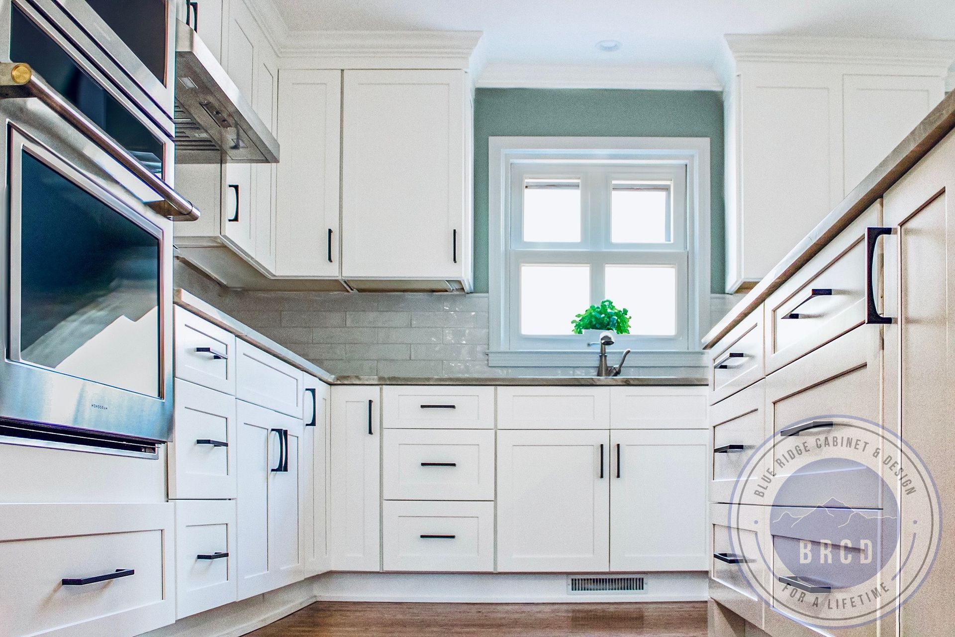 Bright white kitchen with cabinets, stainless appliances, and a window over the sink