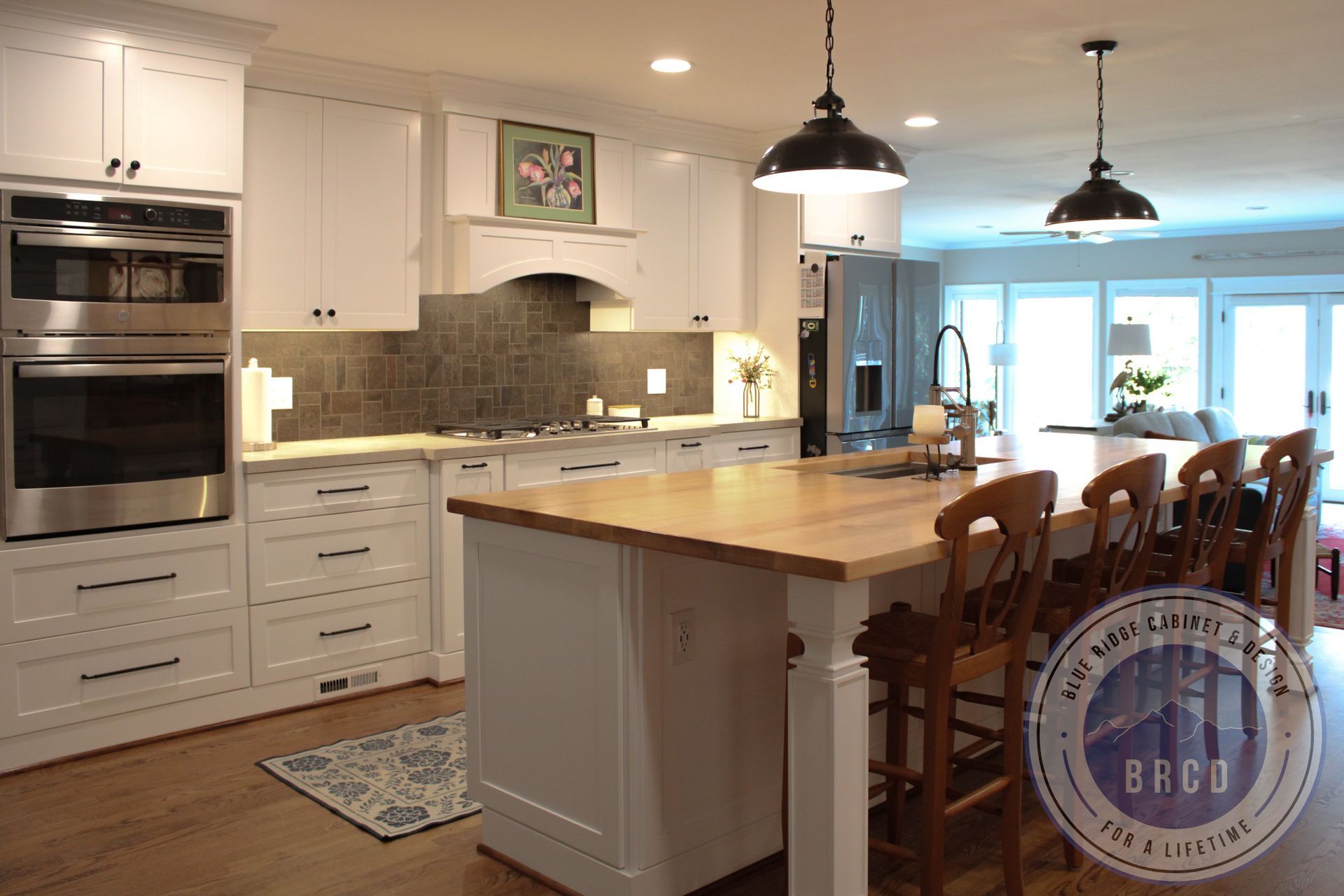 Bright kitchen with white cabinets, wood island, pendant lights, and a dining table by sliding glass doors