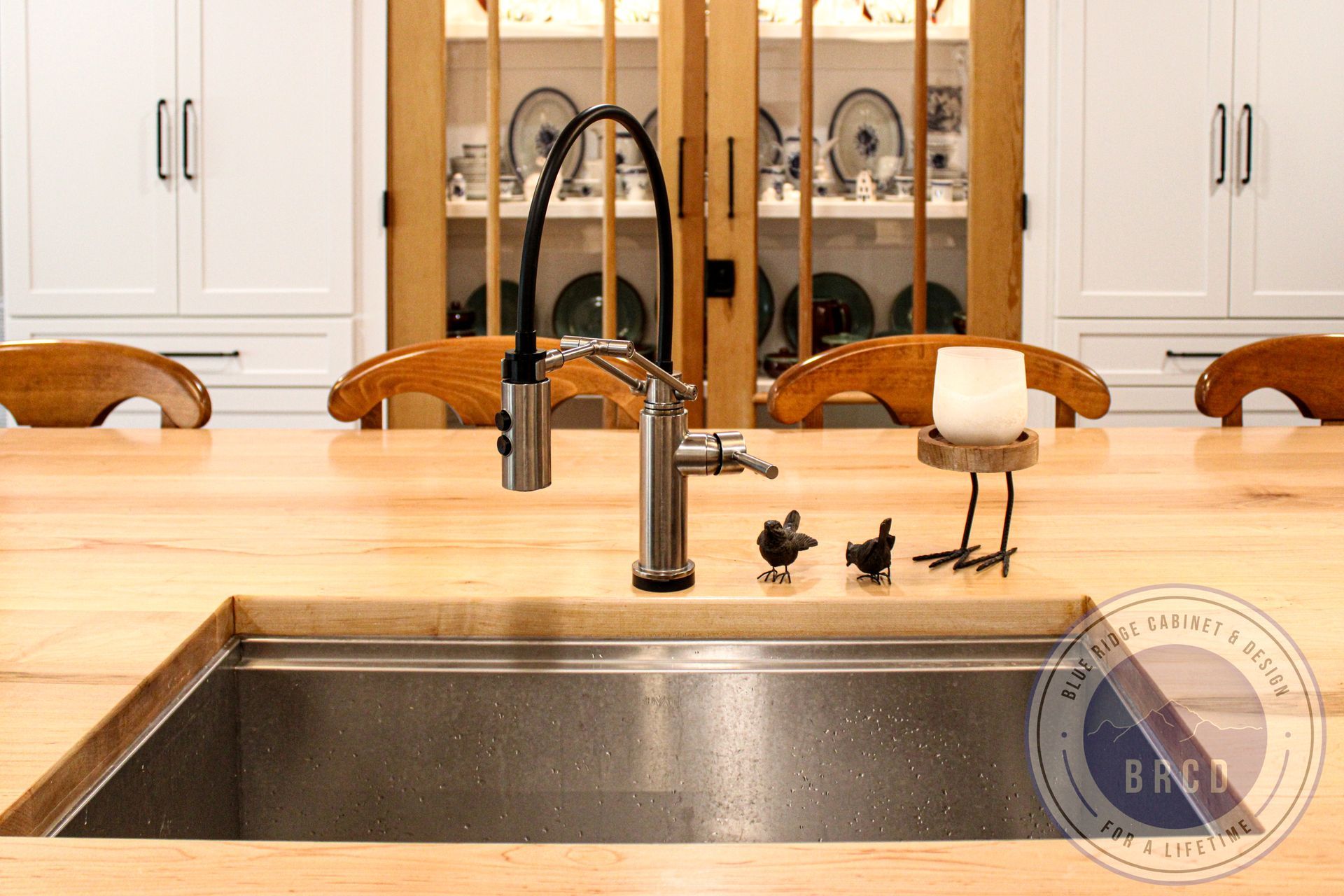 Modern kitchen sink with black faucet, soap dispenser, and wooden stools in the background