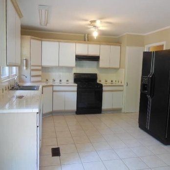 Empty kitchen with white cabinets, black appliances, and tiled floor