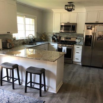Modern kitchen with granite island, two stools, stainless steel appliances, and large window
