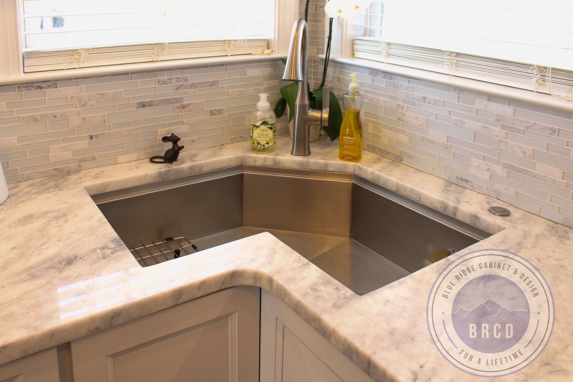 Modern kitchen corner sink with stainless steel basin, light stone countertop, and chrome faucet