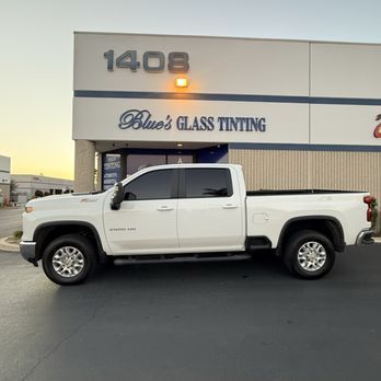 White pickup truck parked outside Blue’s Glass Tinting at dusk.