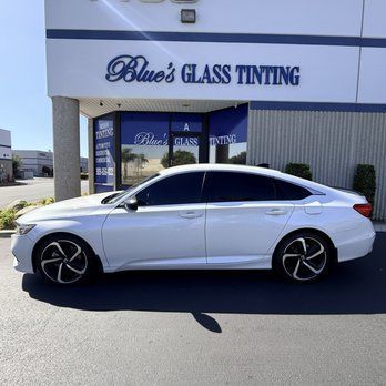 White sedan parked outside Blue’s Glass Tinting shop on a sunny day