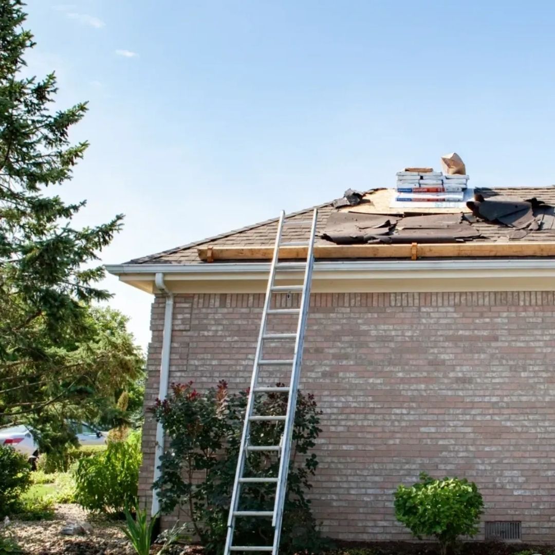A ladder is sitting on the roof of a brick house