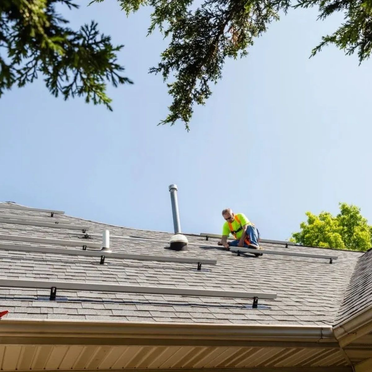 A man is installing solar panels on the roof of a house