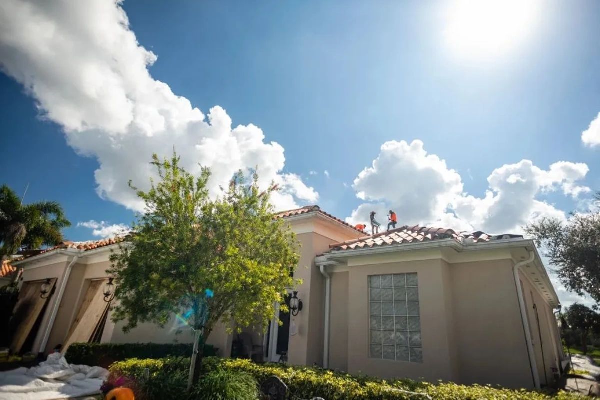 Two men are working on the roof of a house.