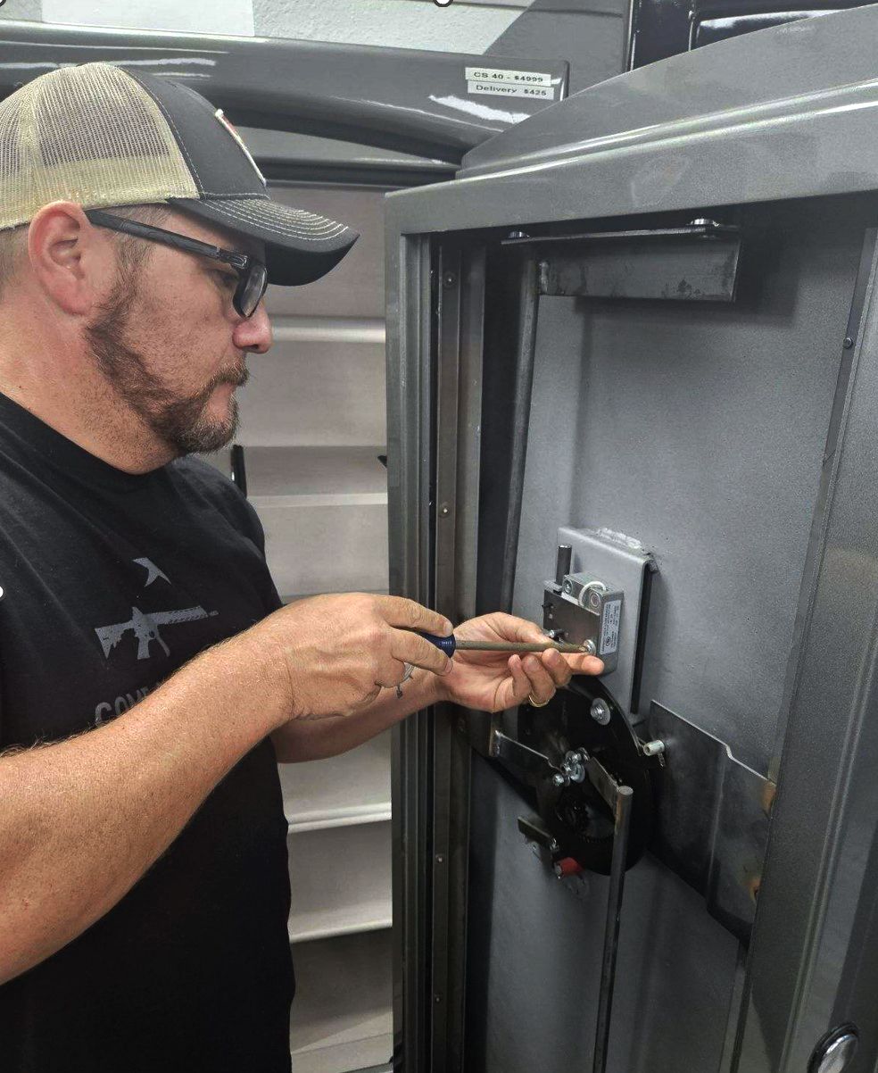 A man is working on a safe with a screwdriver