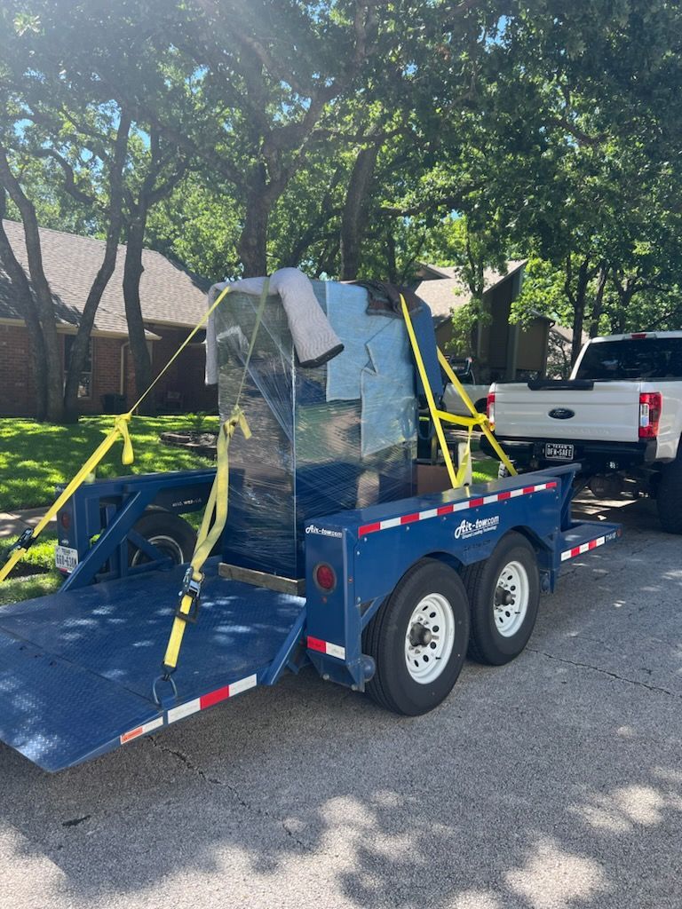 A blue trailer is being towed by a white truck