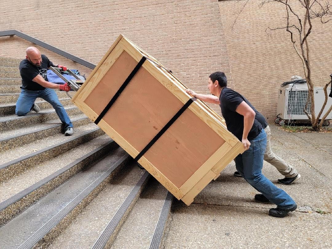 Two men moving a safe to the top of the stairs