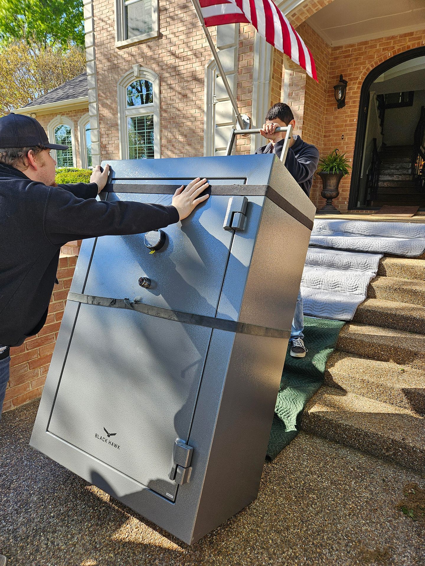 Two men are carrying a large safe into a house