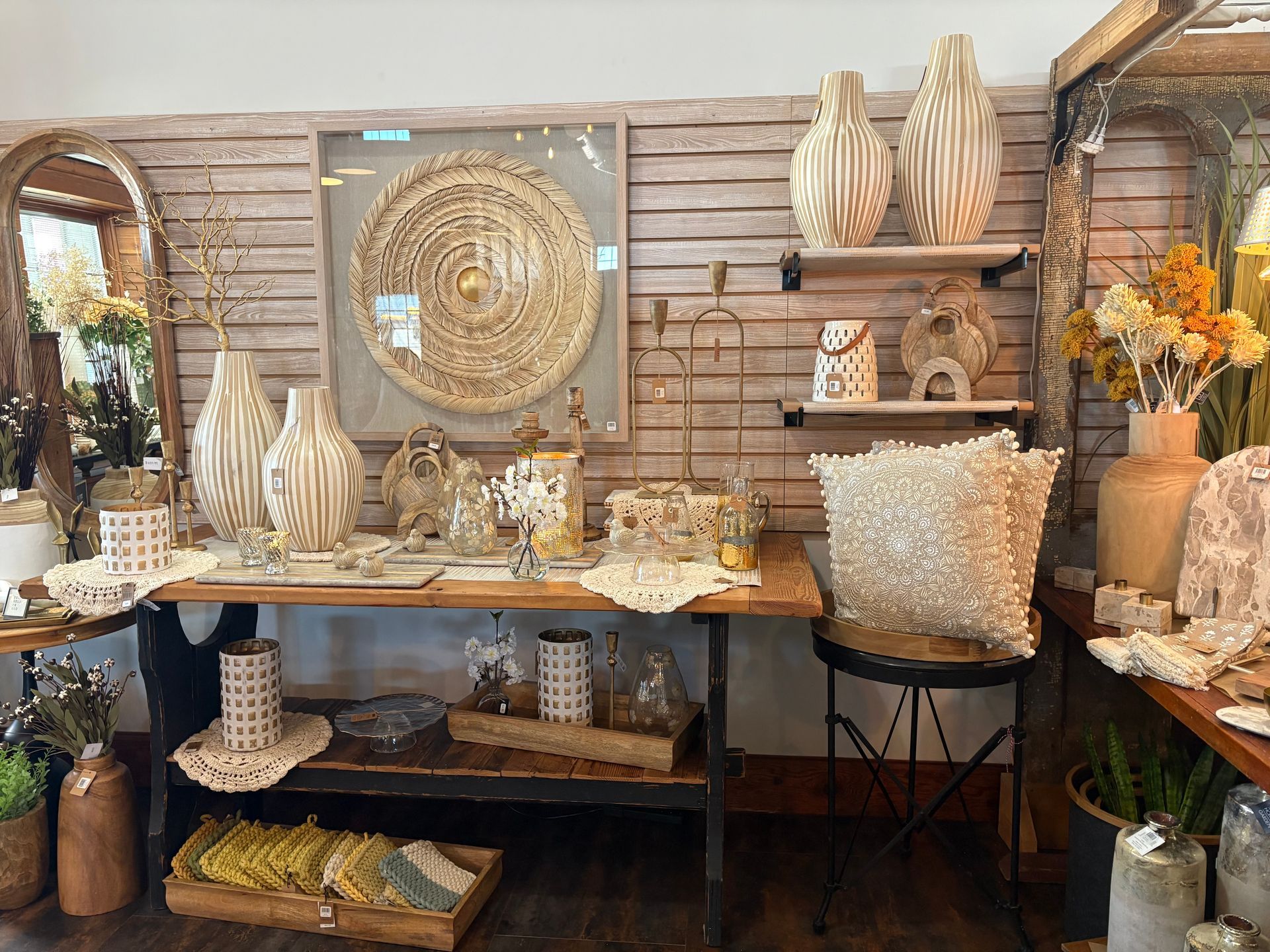 A room with a table, chairs, vases and a mirror.