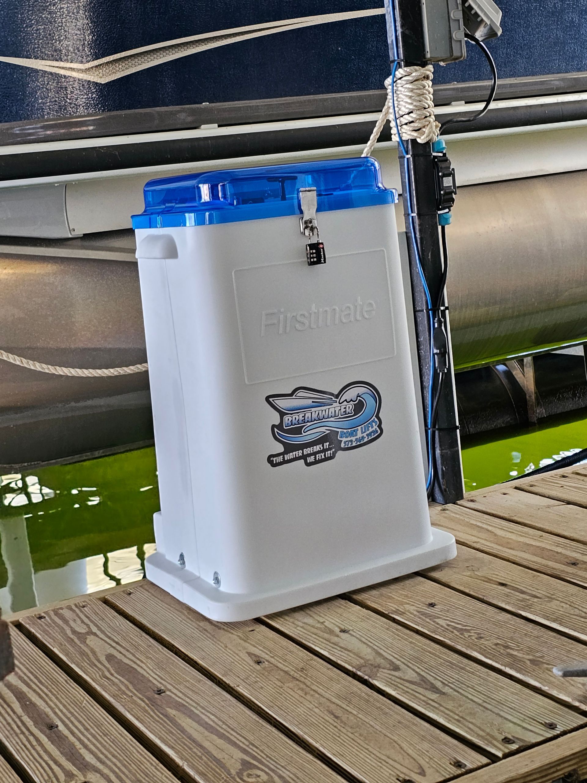 A white and blue container is sitting on a wooden dock next to a boat.