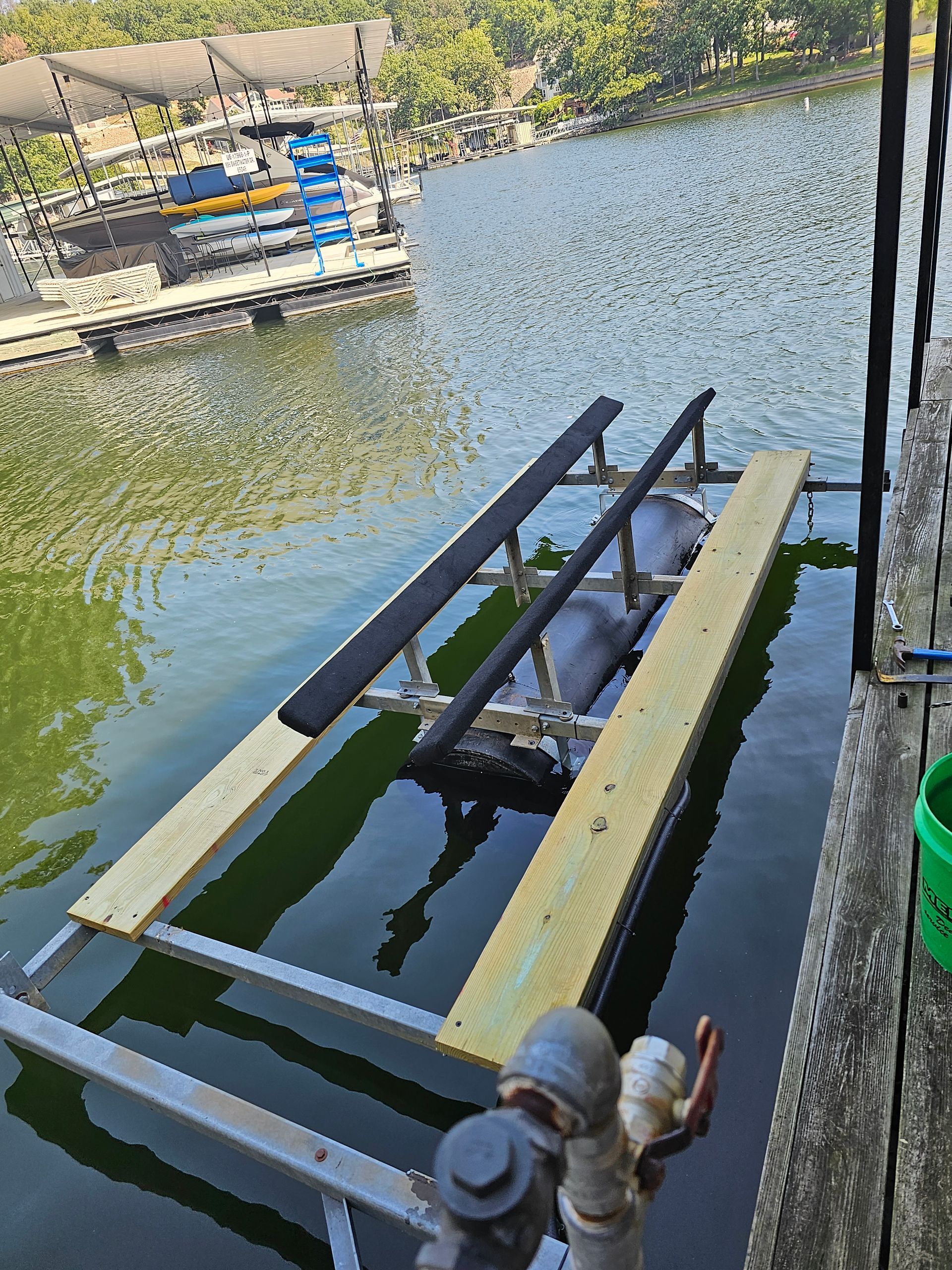 A boat lift is sitting in the water next to a dock.