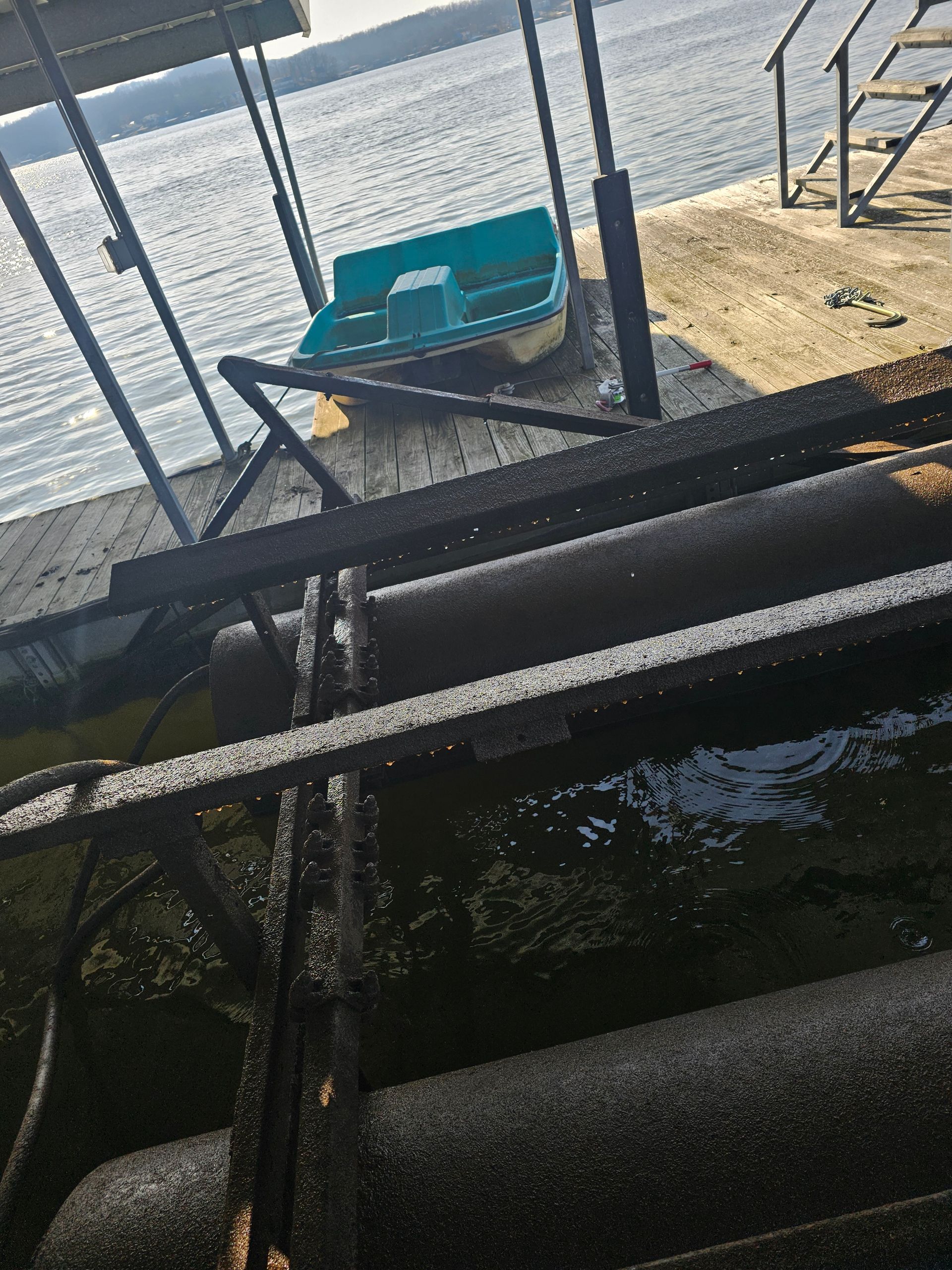 A blue boat is sitting on a dock next to a body of water.