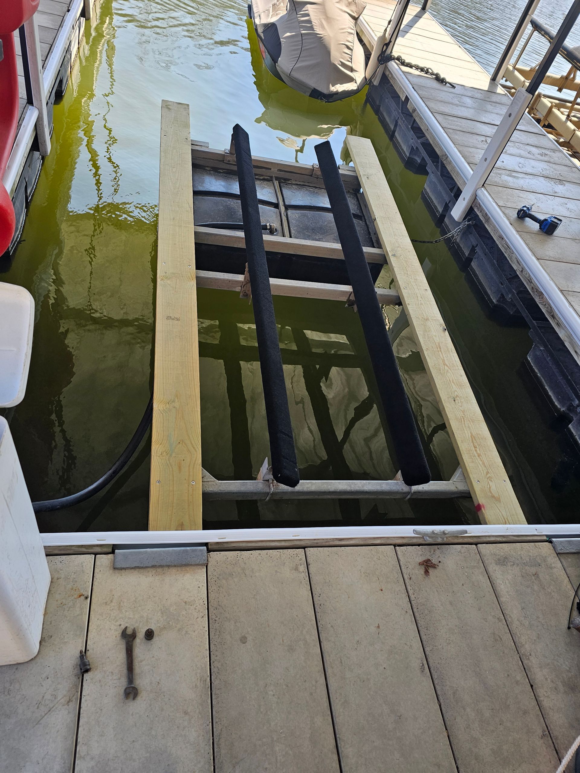 A boat is being lifted into the water by a wooden ramp.