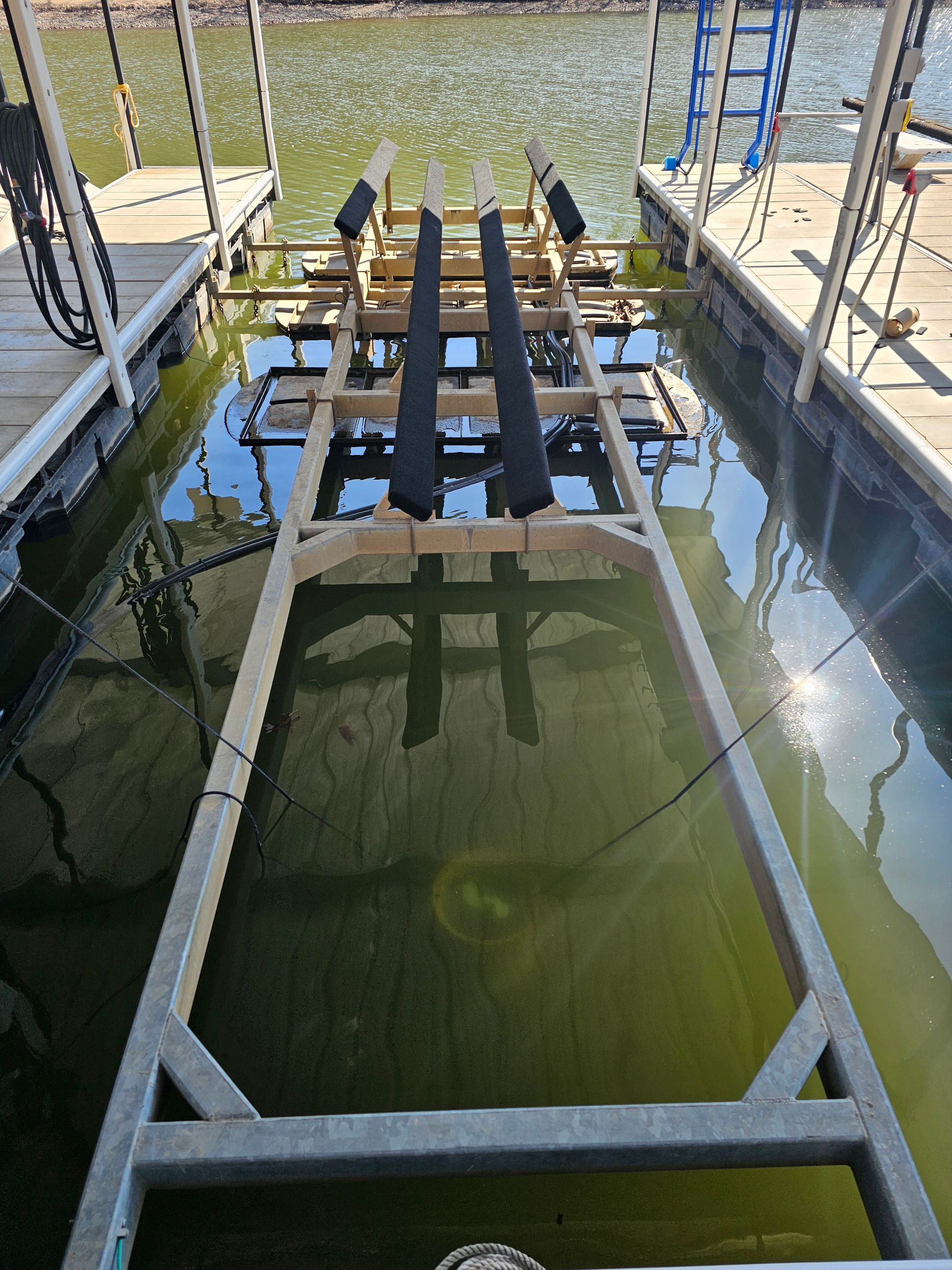 A boat lift is sitting in the water at a dock.