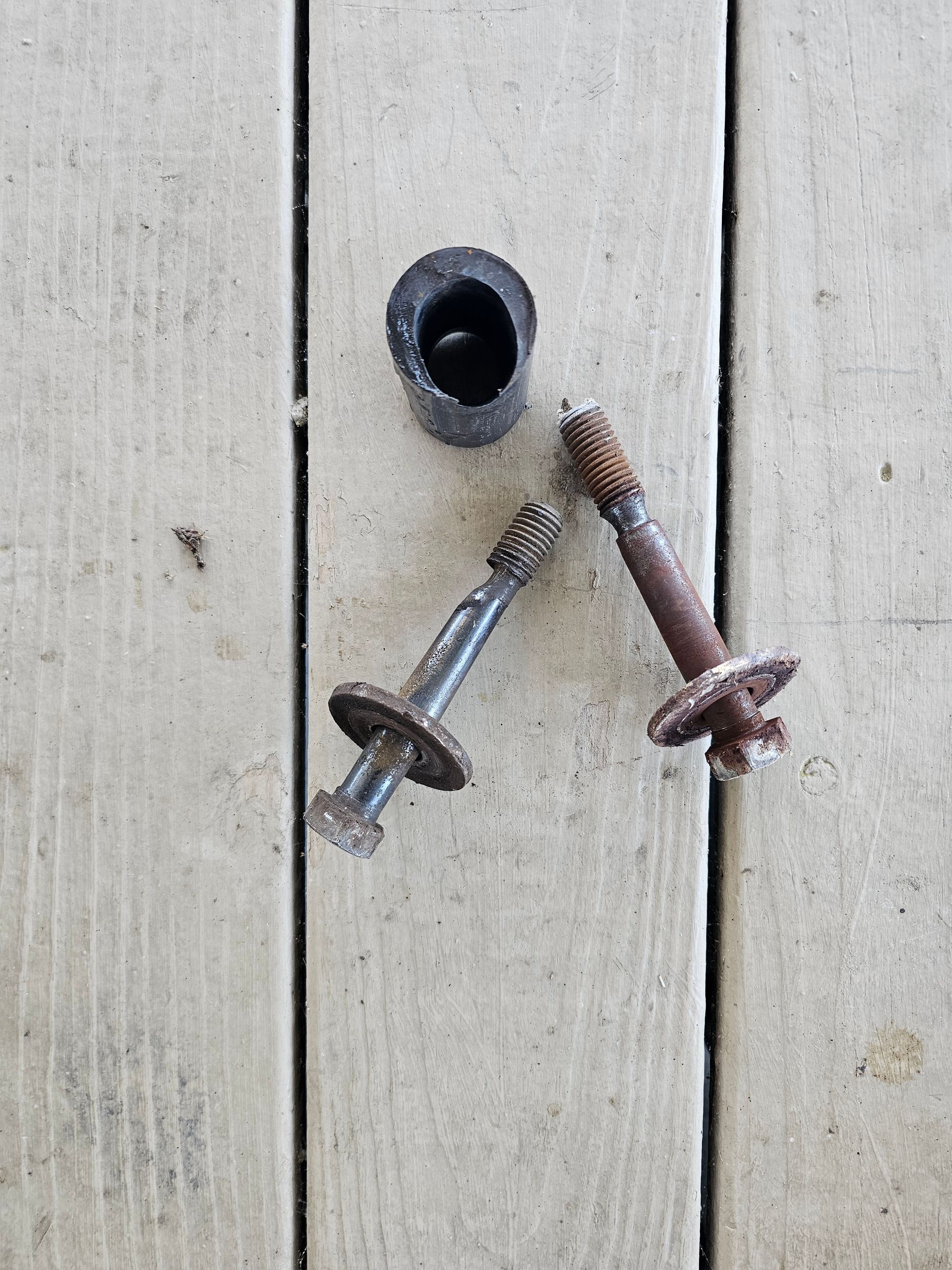 Two rusty screws are sitting on a wooden table.