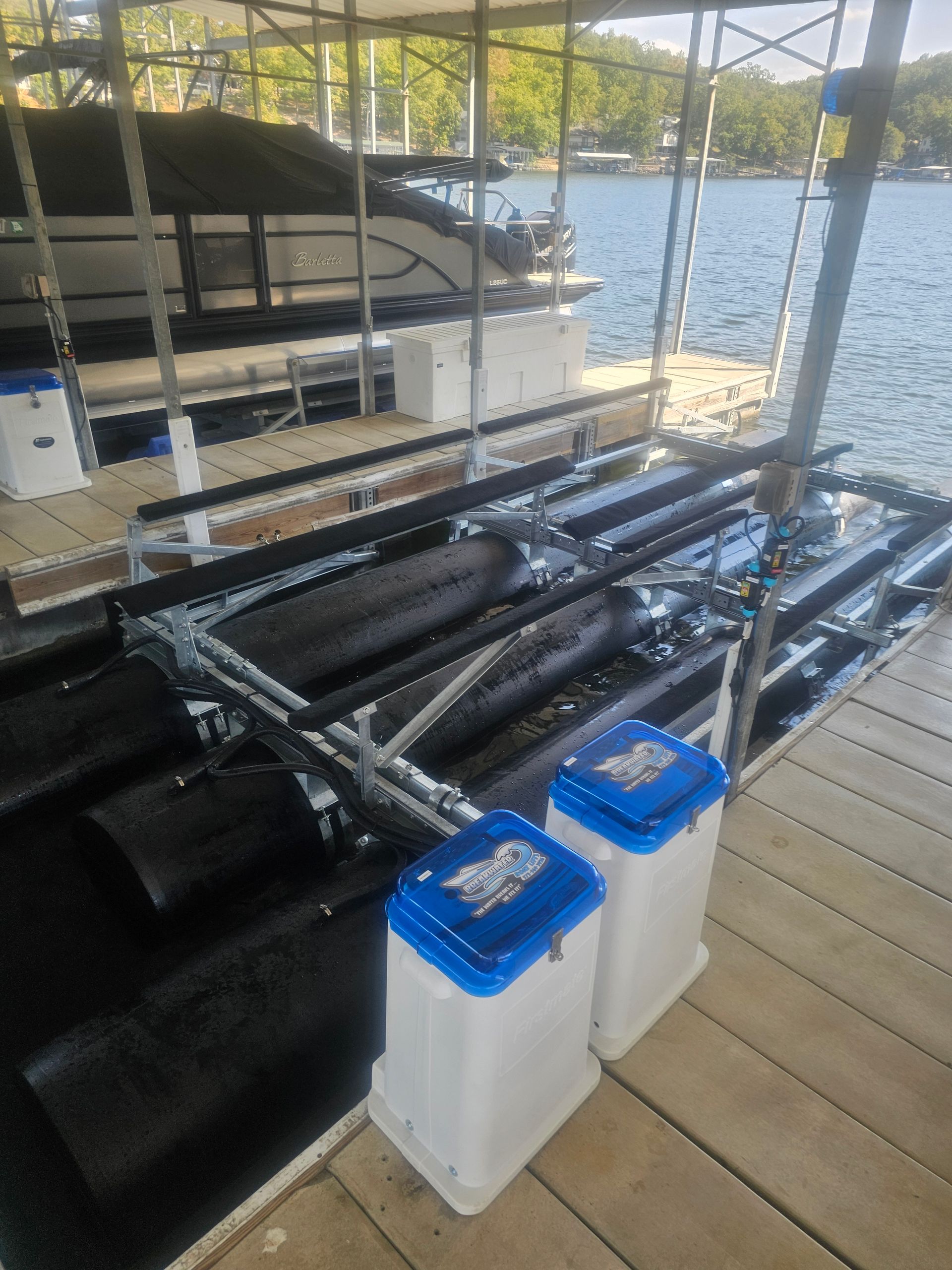 A boat is docked at a dock with two trash cans next to it.