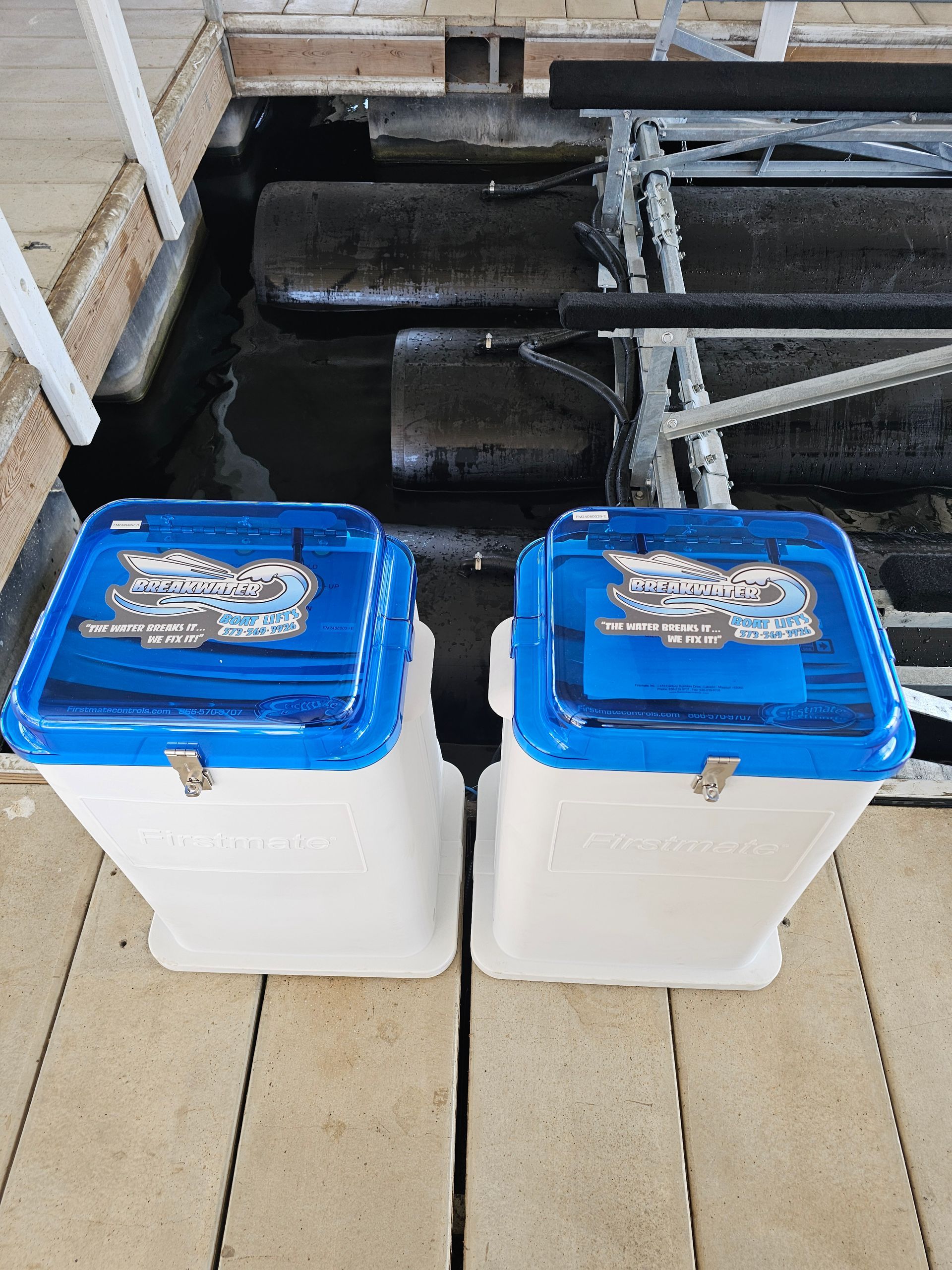 Two white containers with blue lids are sitting on a wooden deck.