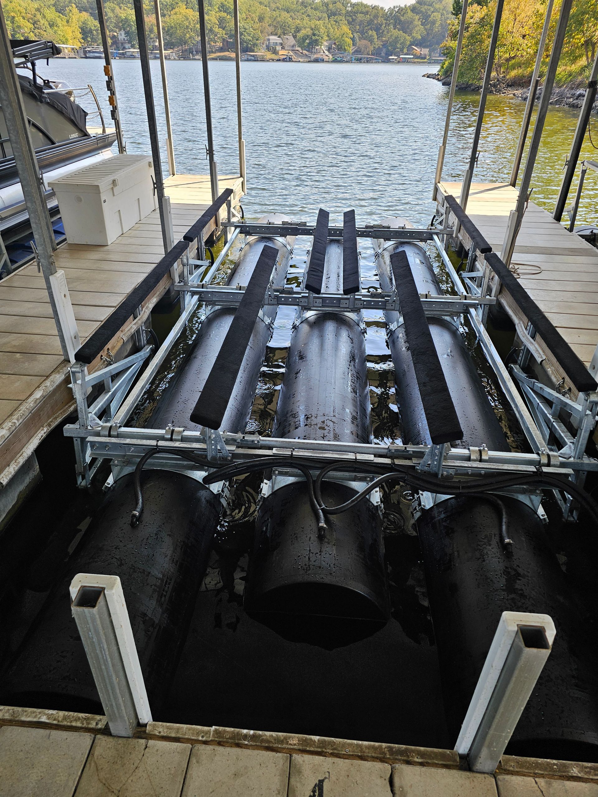 A boat trailer is sitting on top of a dock next to a body of water.