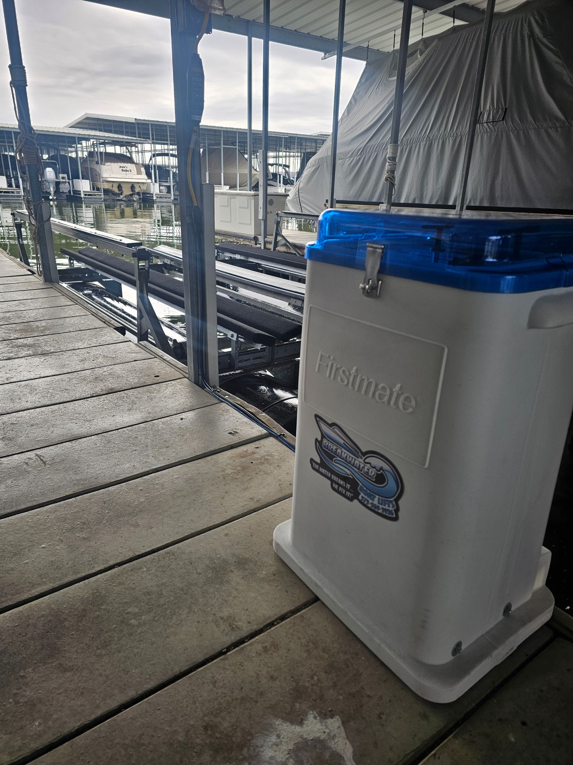 A white cooler with a blue lid is sitting on a wooden deck.