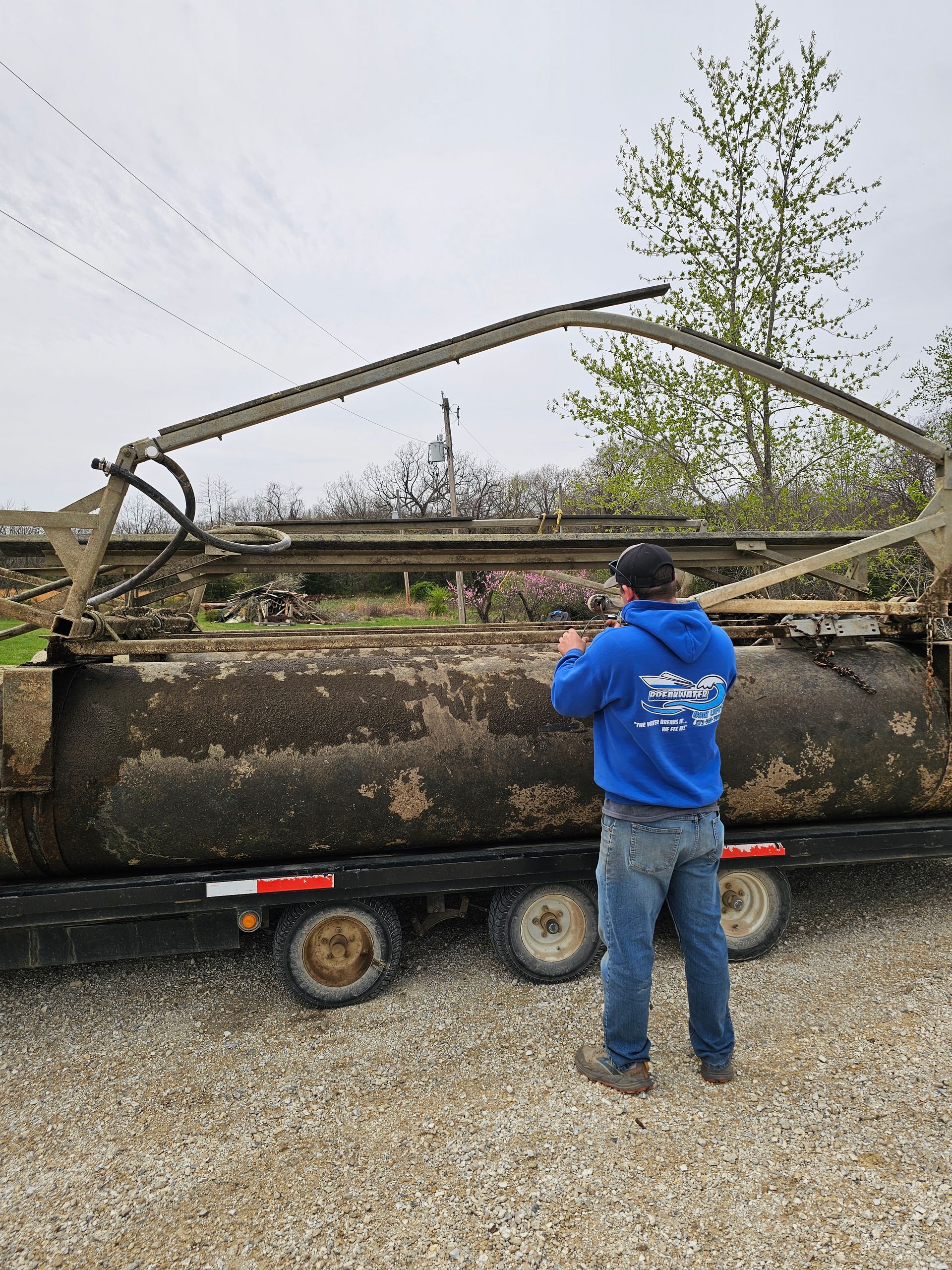 A man in a blue hoodie is standing in front of a trailer