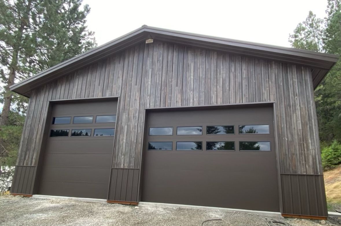 A garage with two garage doors and a wooden siding.