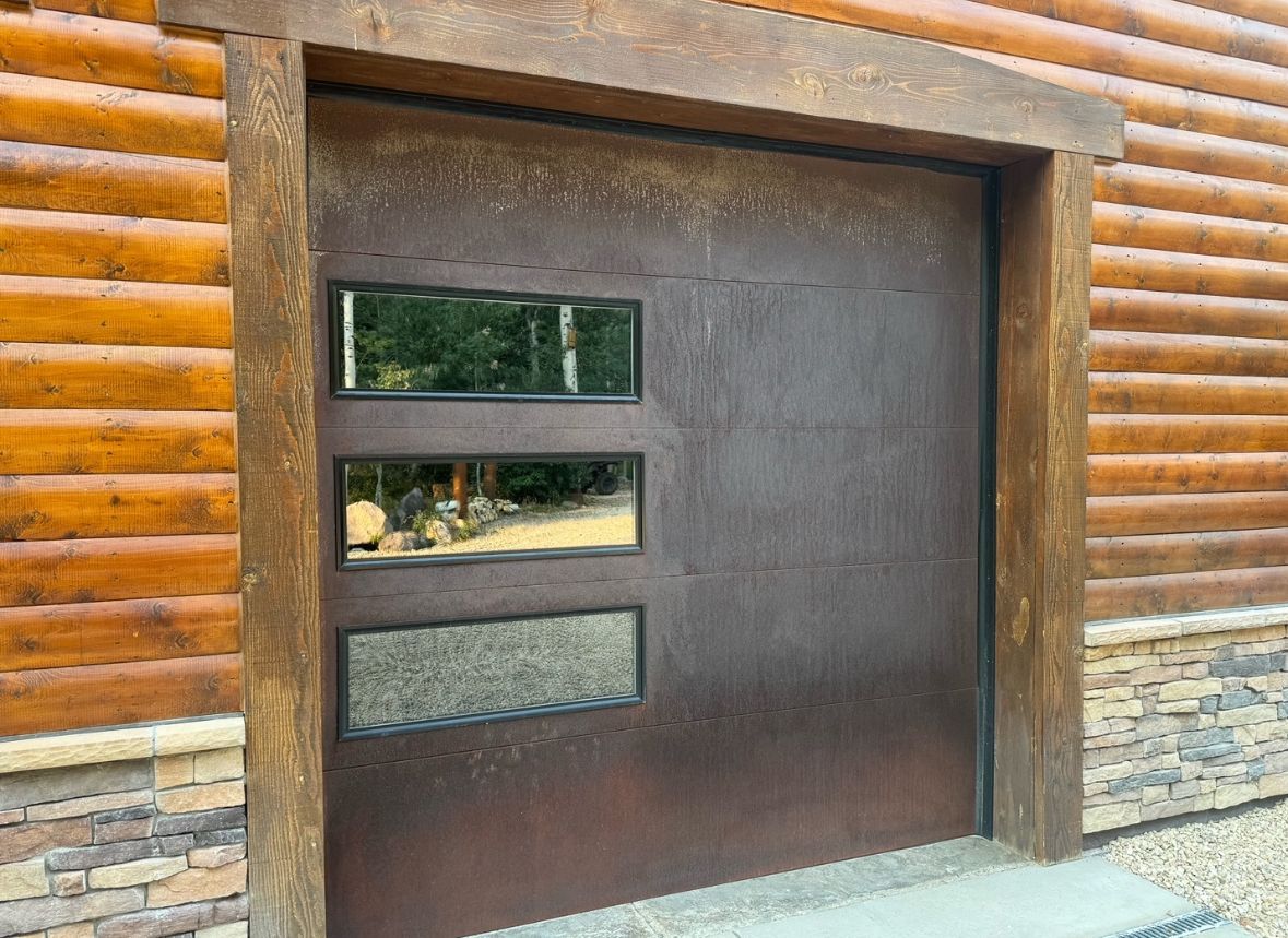 A brown garage door is sitting on the side of a log cabin.