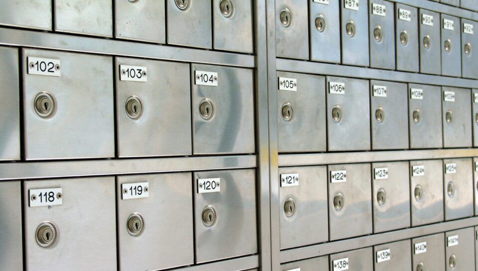 Rows of gray metal mailboxes with numbered doors in a storage or apartment mailbox area