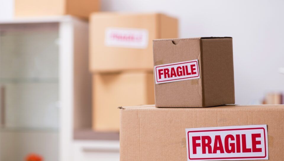 Stacked cardboard boxes with red FRAGILE labels in a moving/storage room