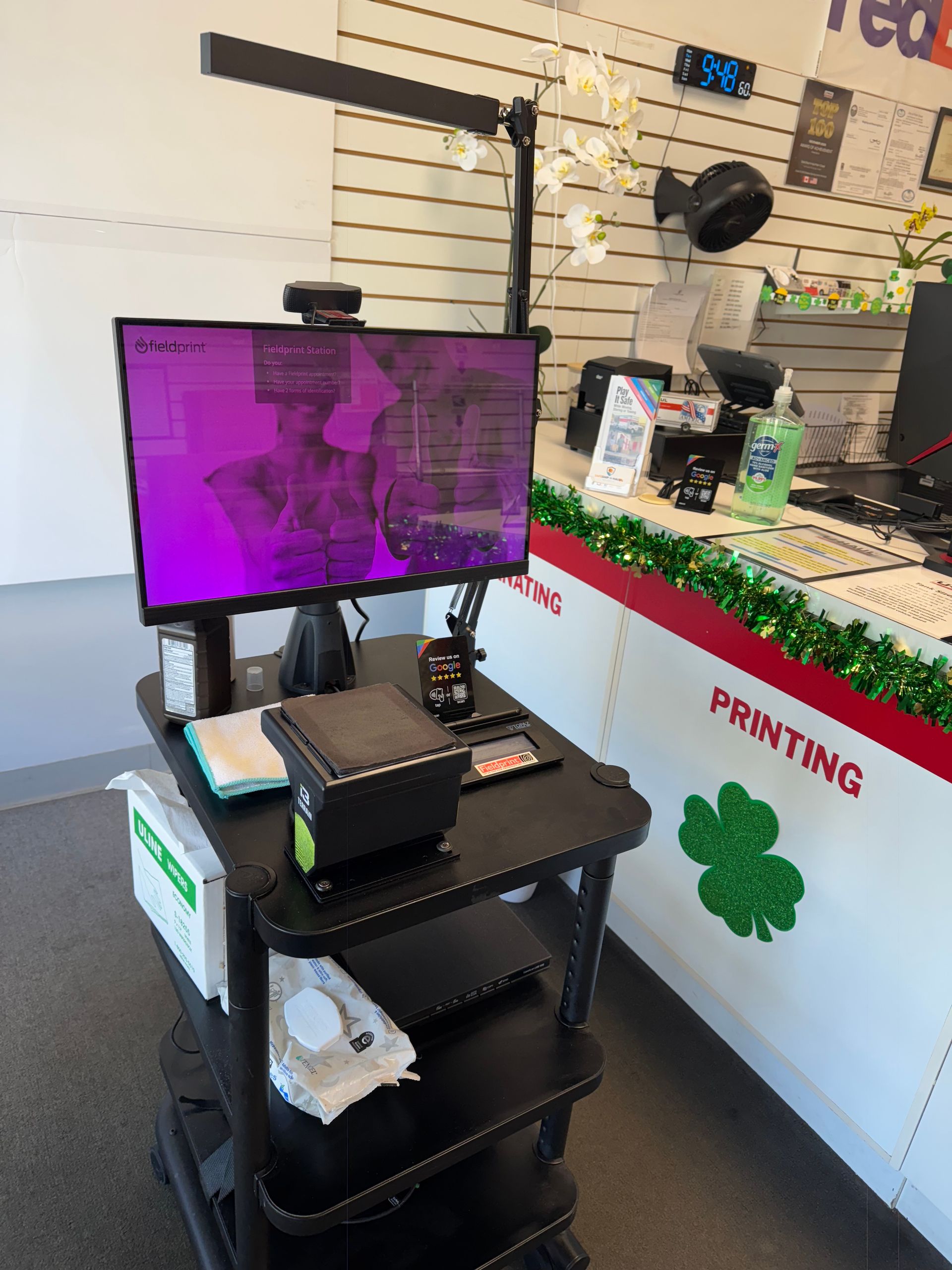 Retail kiosk with monitor, printer, and barcode scanner on a cart in a store printing area