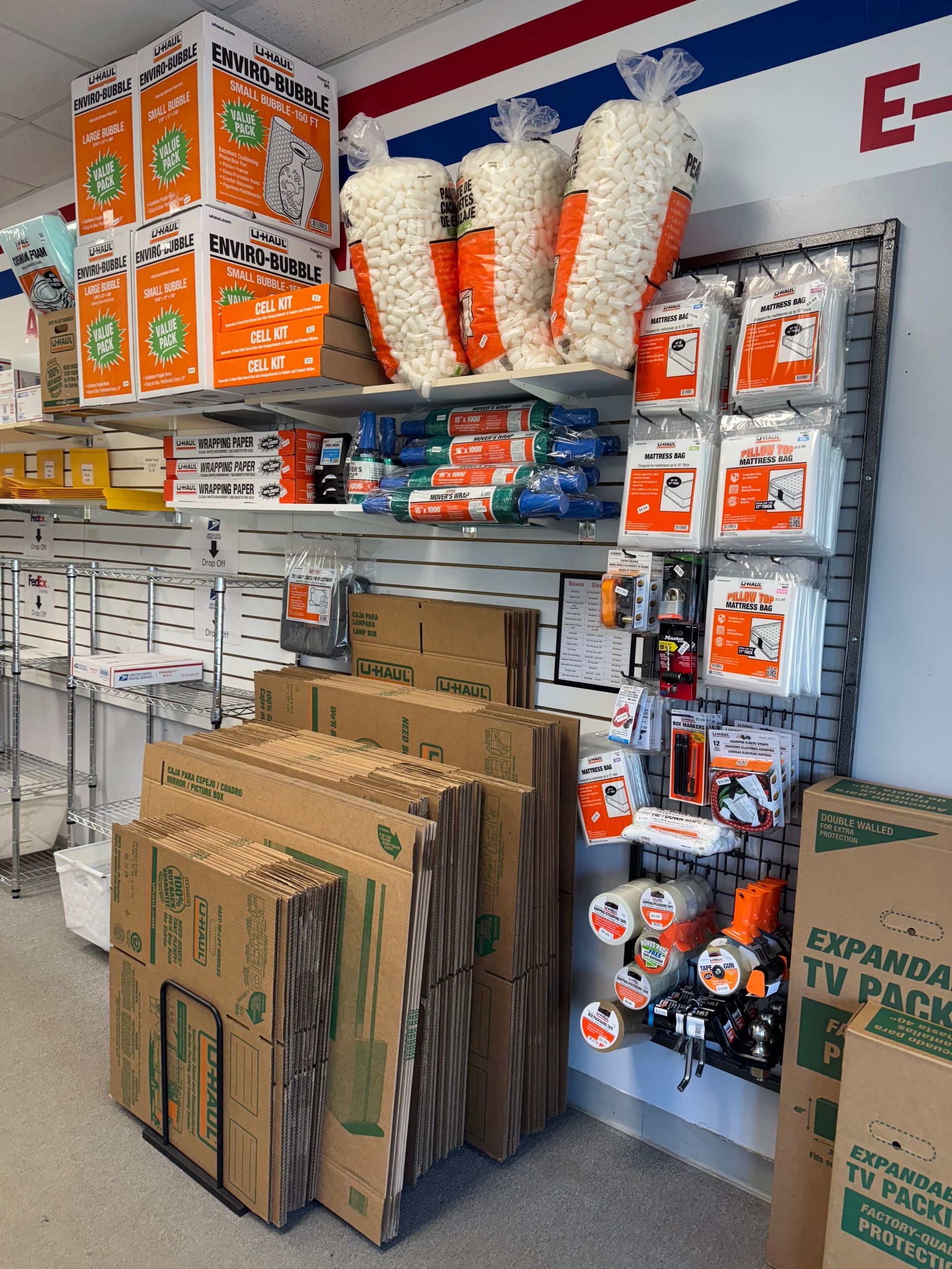 Shelves of packaged party supplies and decorations in a store aisle, with cardboard boxes stacked in front.