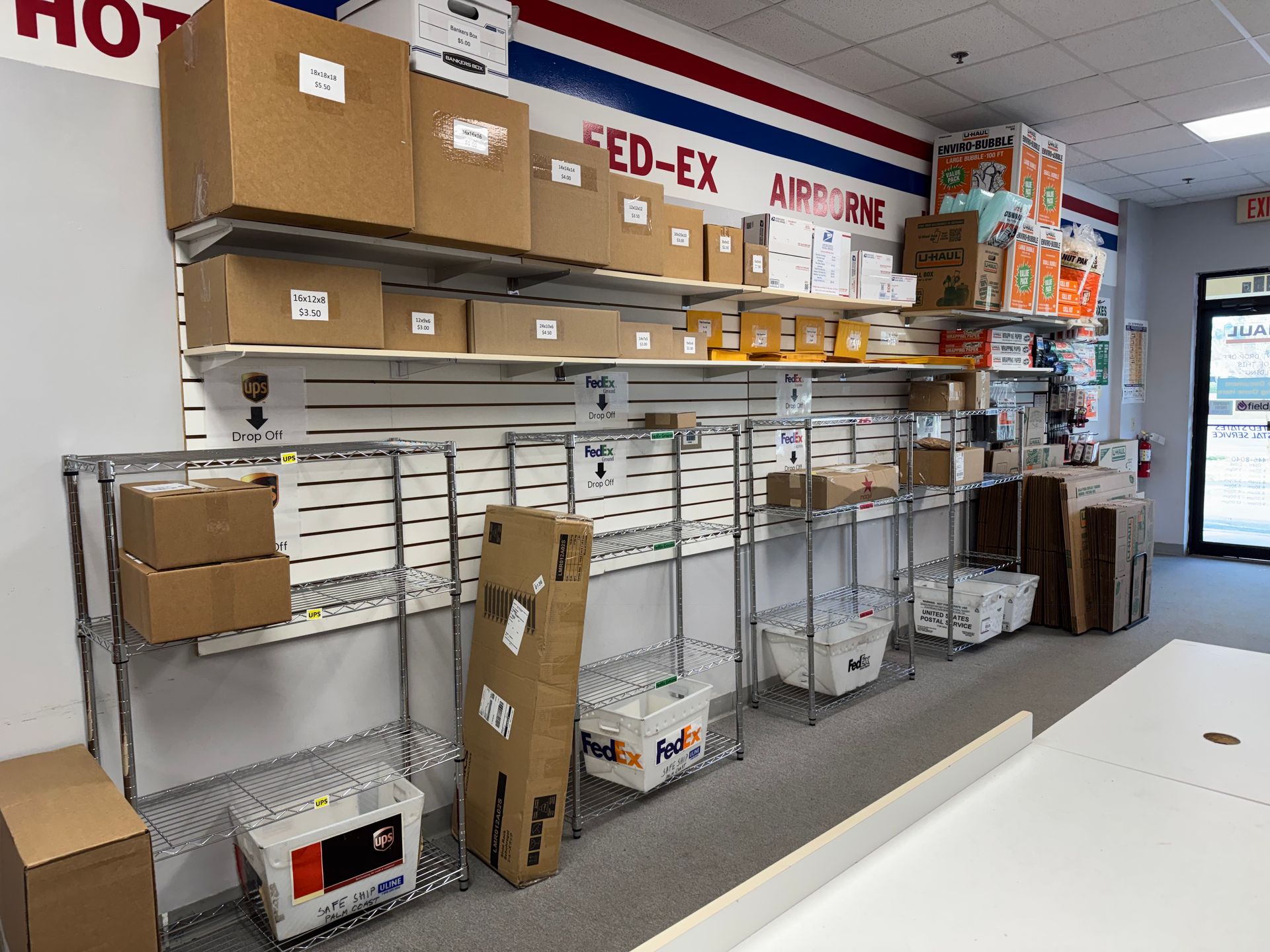 Storage shelves in a FedEx shipping area with stacked boxes and office supplies