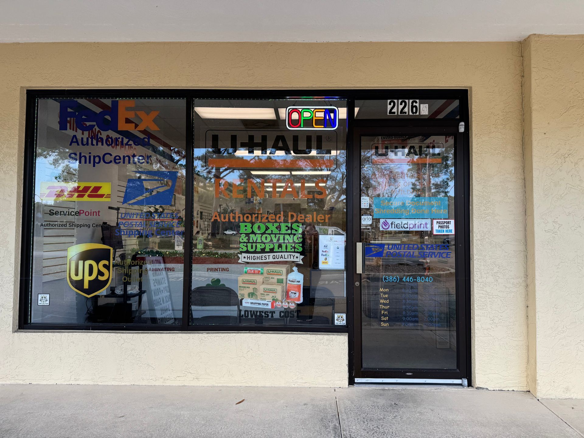 Storefront with FedEx, DHL, and UPS signs, beige exterior, and a glass entrance door