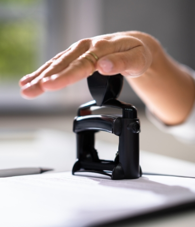 Hand stamping a black rubber date stamp onto a document
