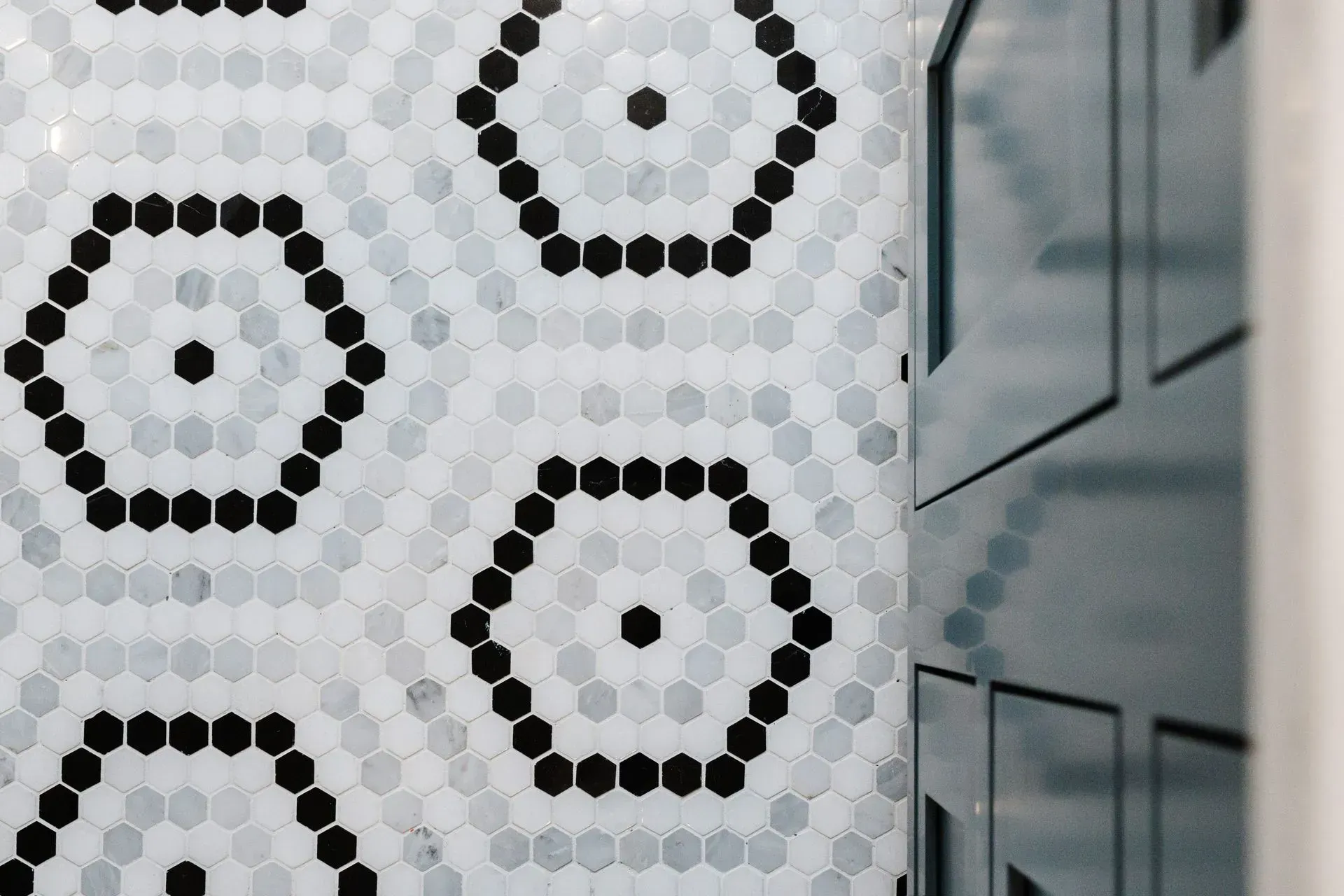 Black-and-white geometric tile pattern on a wall beside glass-paneled doors