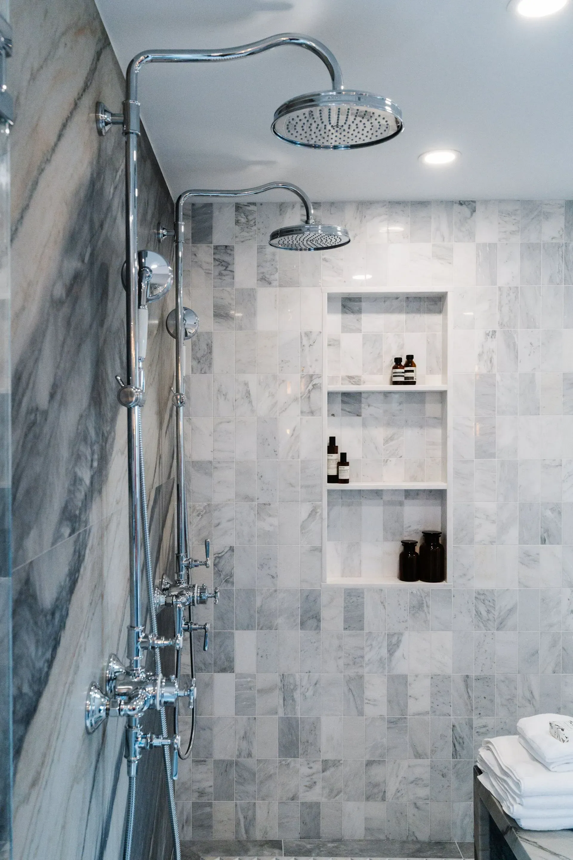 Modern tiled shower with two rainfall showerheads and built-in wall shelves