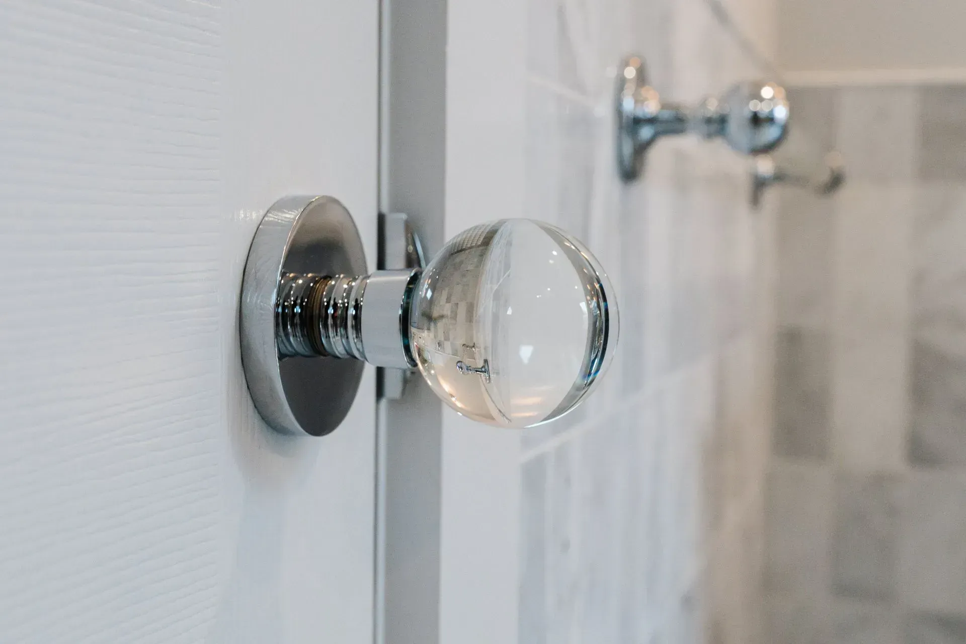 Chrome glass shower door knob on a white bathroom door